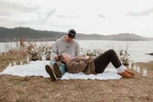 Two people relax together on a blanket with a scenic water view.