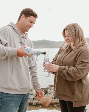 Two people sharing champagne during a celebration by the ocean.