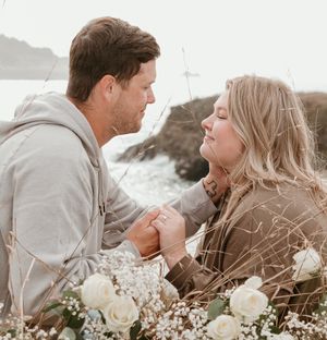 A romantic moment captured on a coastal overlook with white roses and baby's breath flowers.