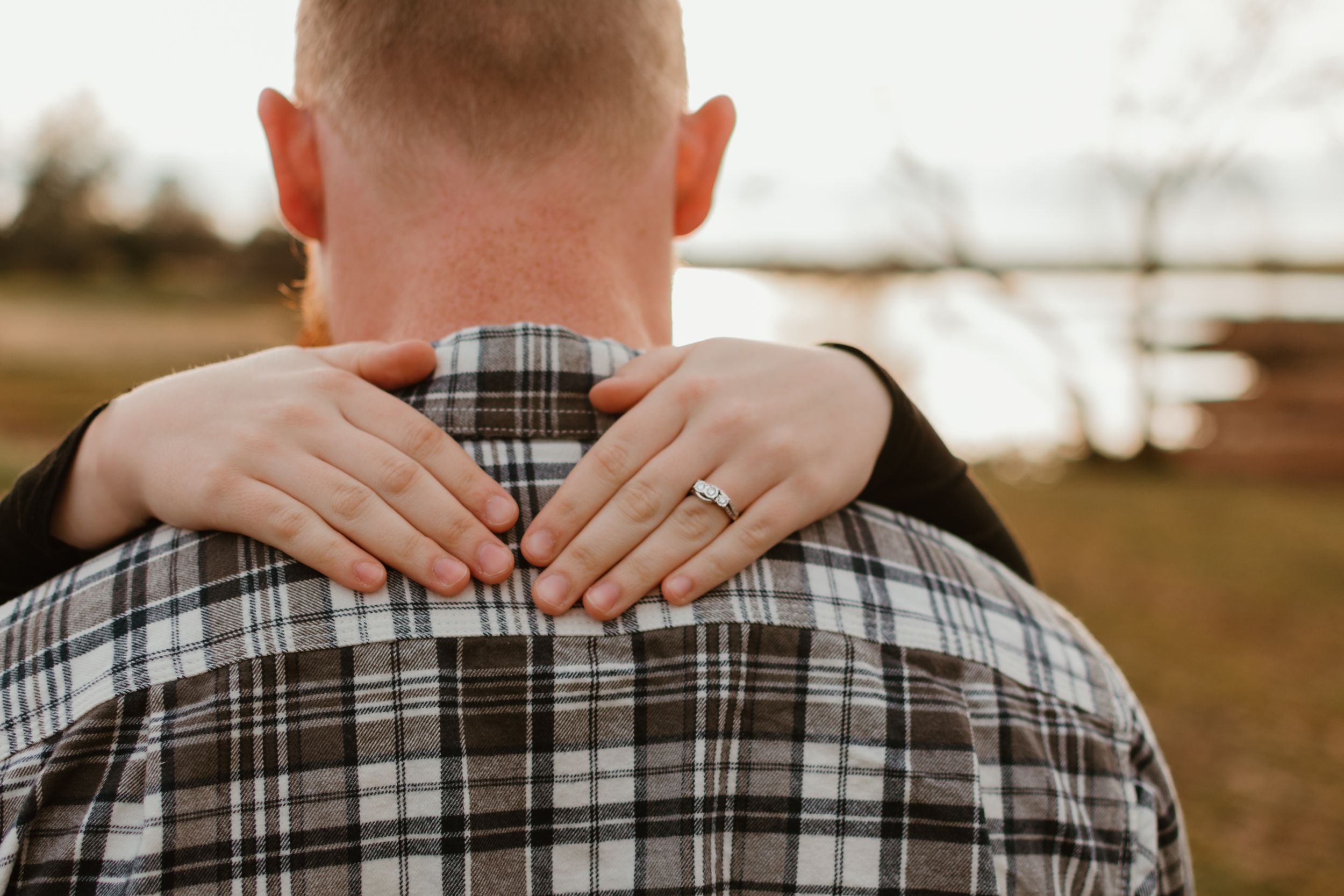 Hands resting on shoulders wearing plaid shirt from behind.