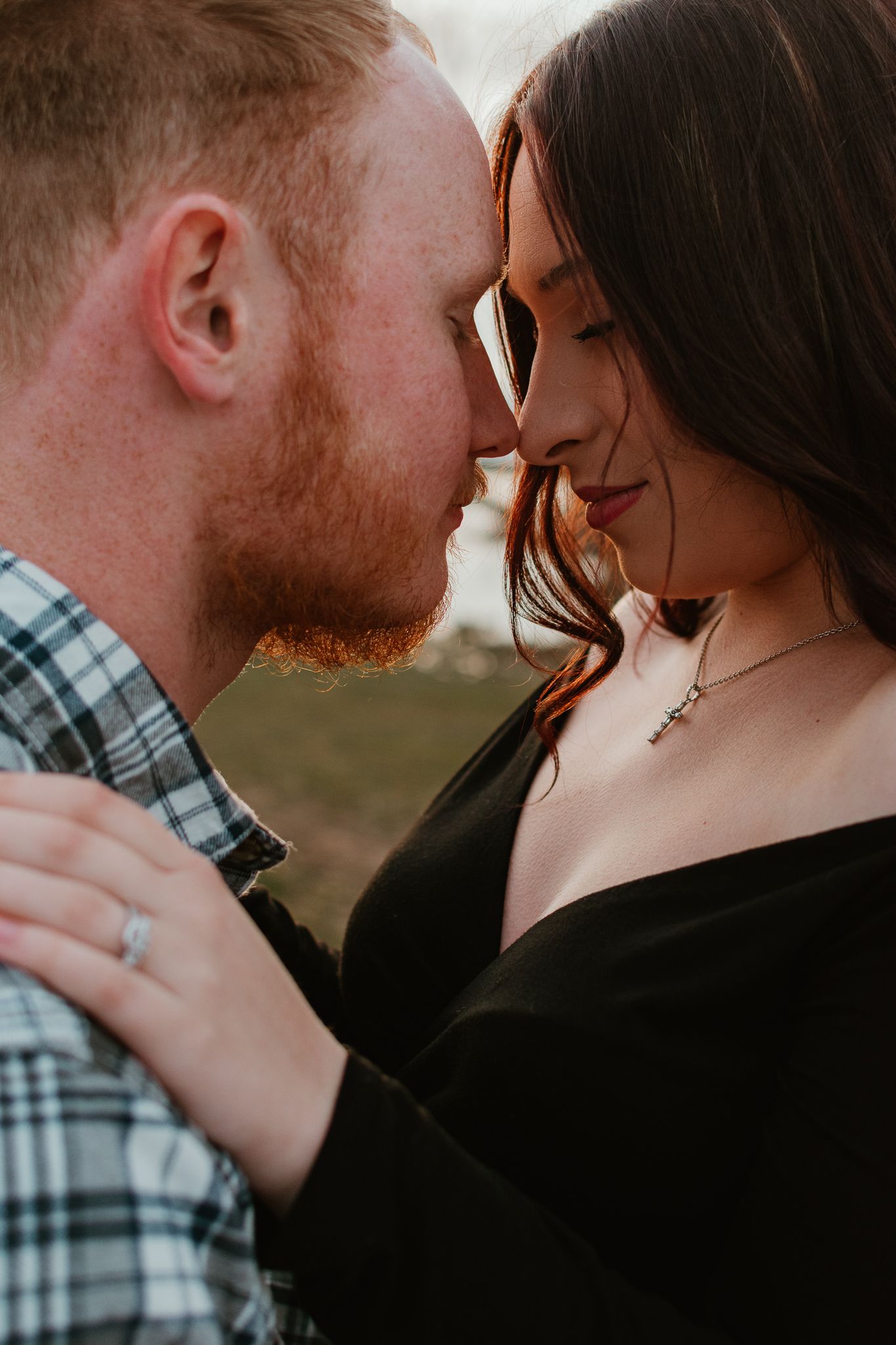 An intimate close-up portrait of a couple sharing a romantic moment outdoors.