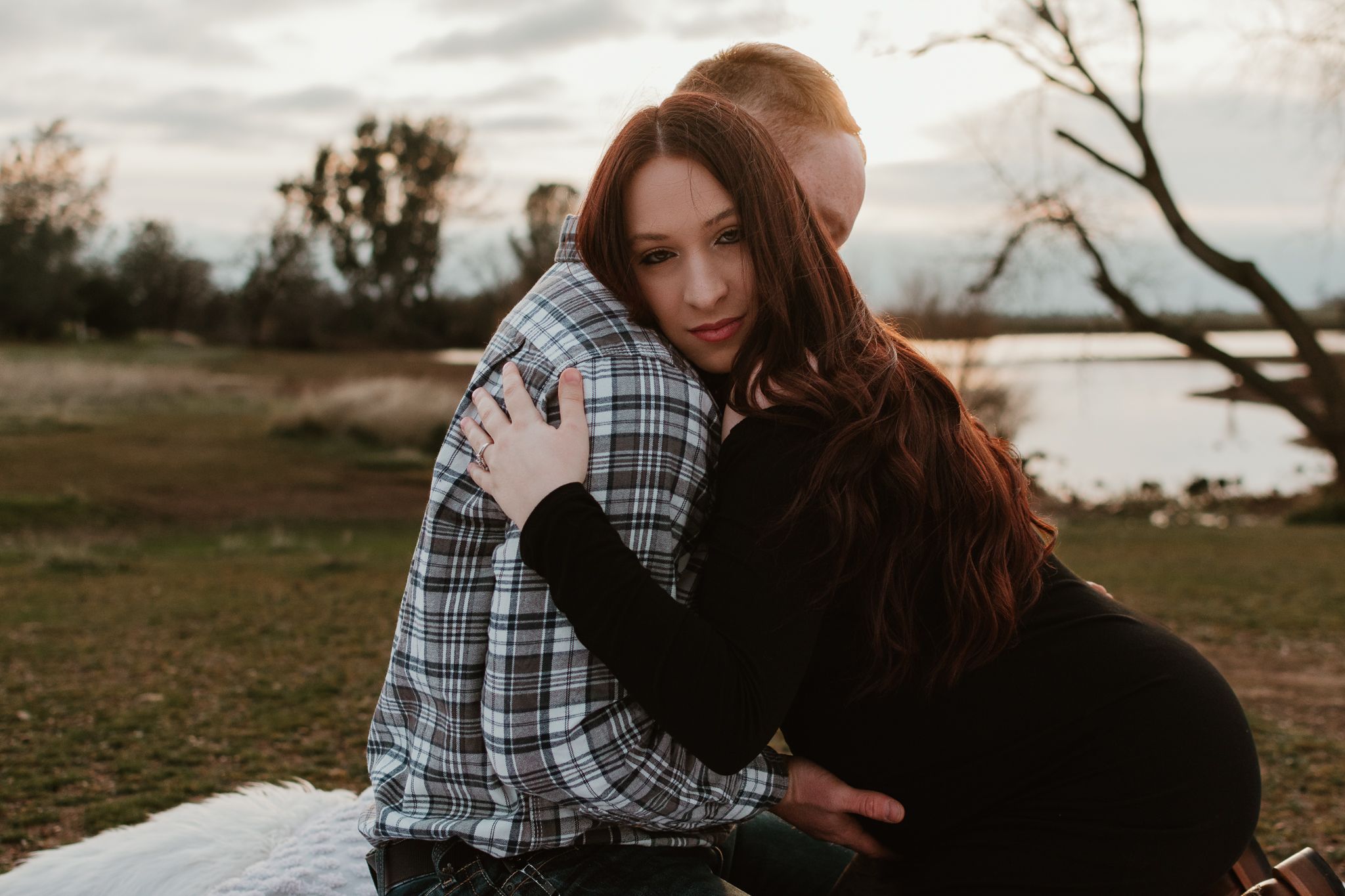 A couple embraces during a romantic outdoor photoshoot at dusk.
