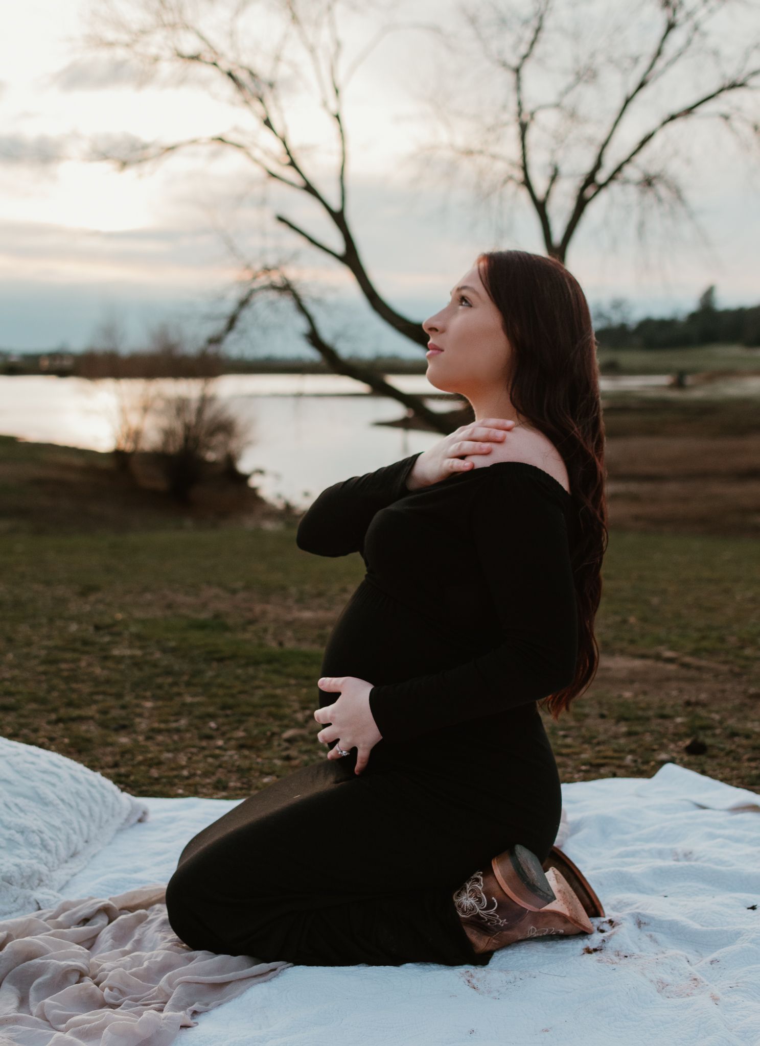 A couple shares emotional moments while sitting on a white blanket outdoors.