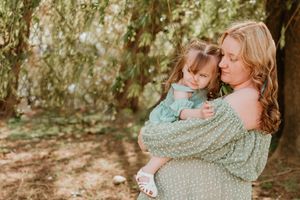 A tender moment captured under willow trees in soft natural lighting.