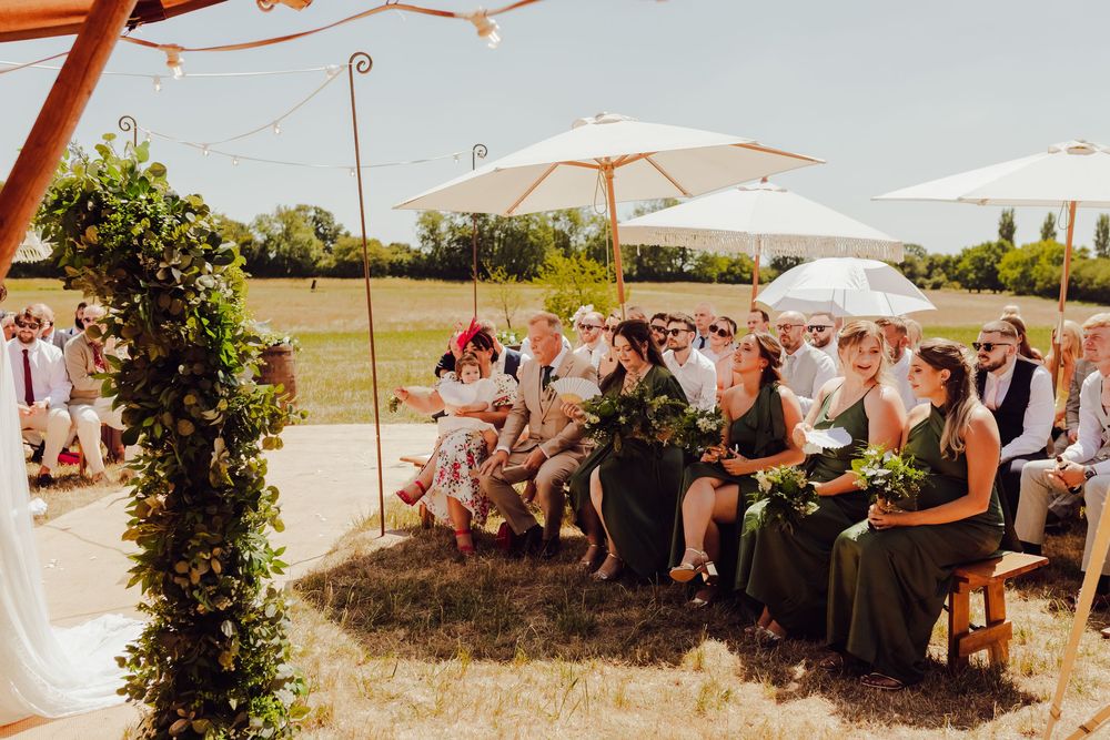 Wedding guests seated on the bridesmaids’ side during Amy and James’ outdoor ceremony.
