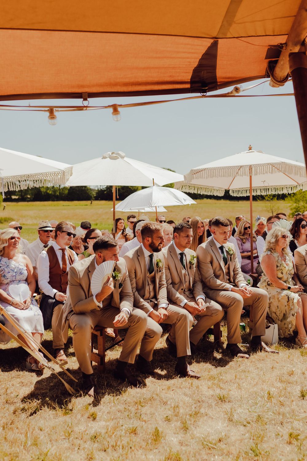 Wedding guests seated on the groomsmen’s side during an outdoor ceremony in Romsey.
