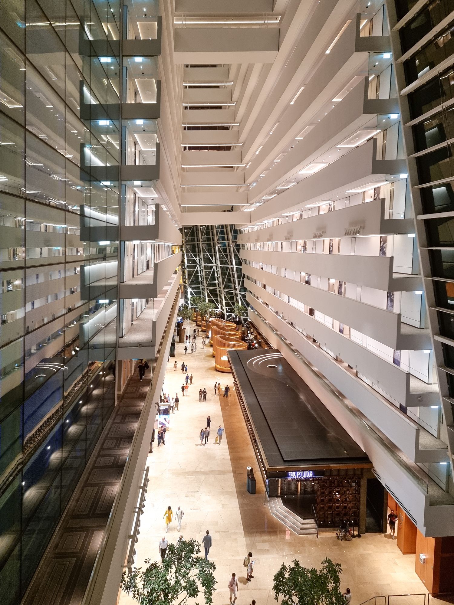 Modern atrium interior of shopping mall with dramatic white terraced levels and glass walls.