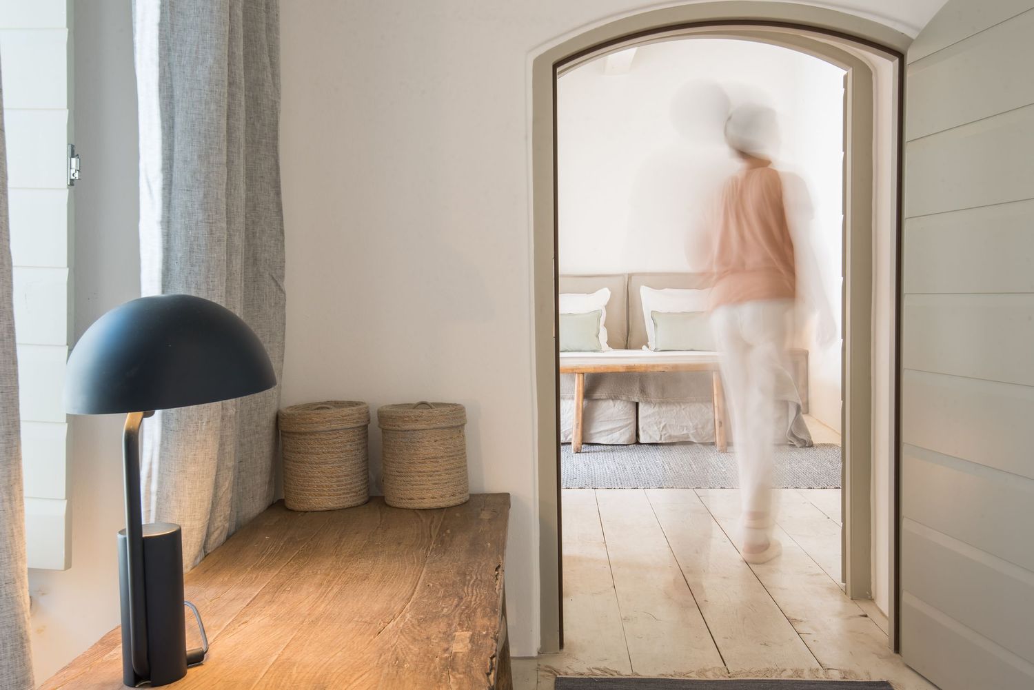 Minimalist interior with black dome lamp and woven baskets beside an arched doorway.