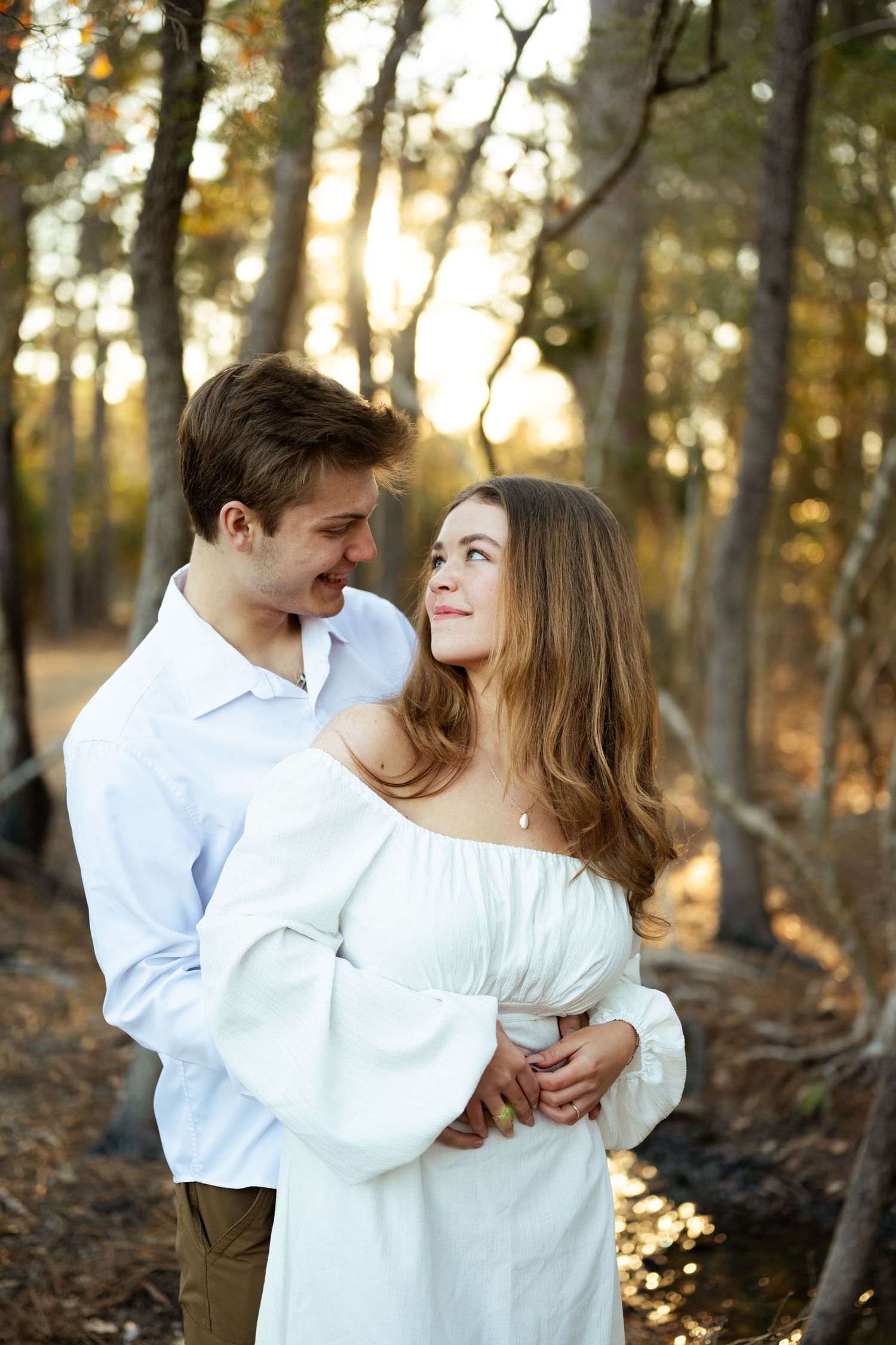 Intimate couple portrait under a wooden pier structure.