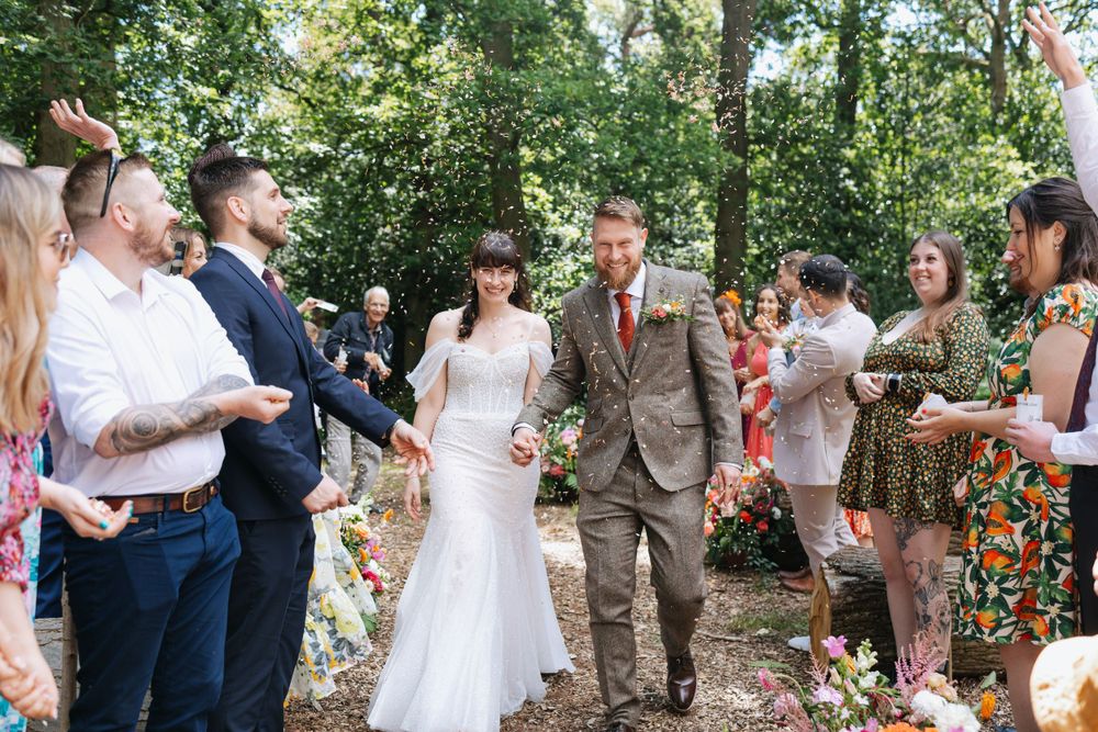 Guests hold bubbles wands in a sunny wooded setting during an intimate outdoor wedding celebration.