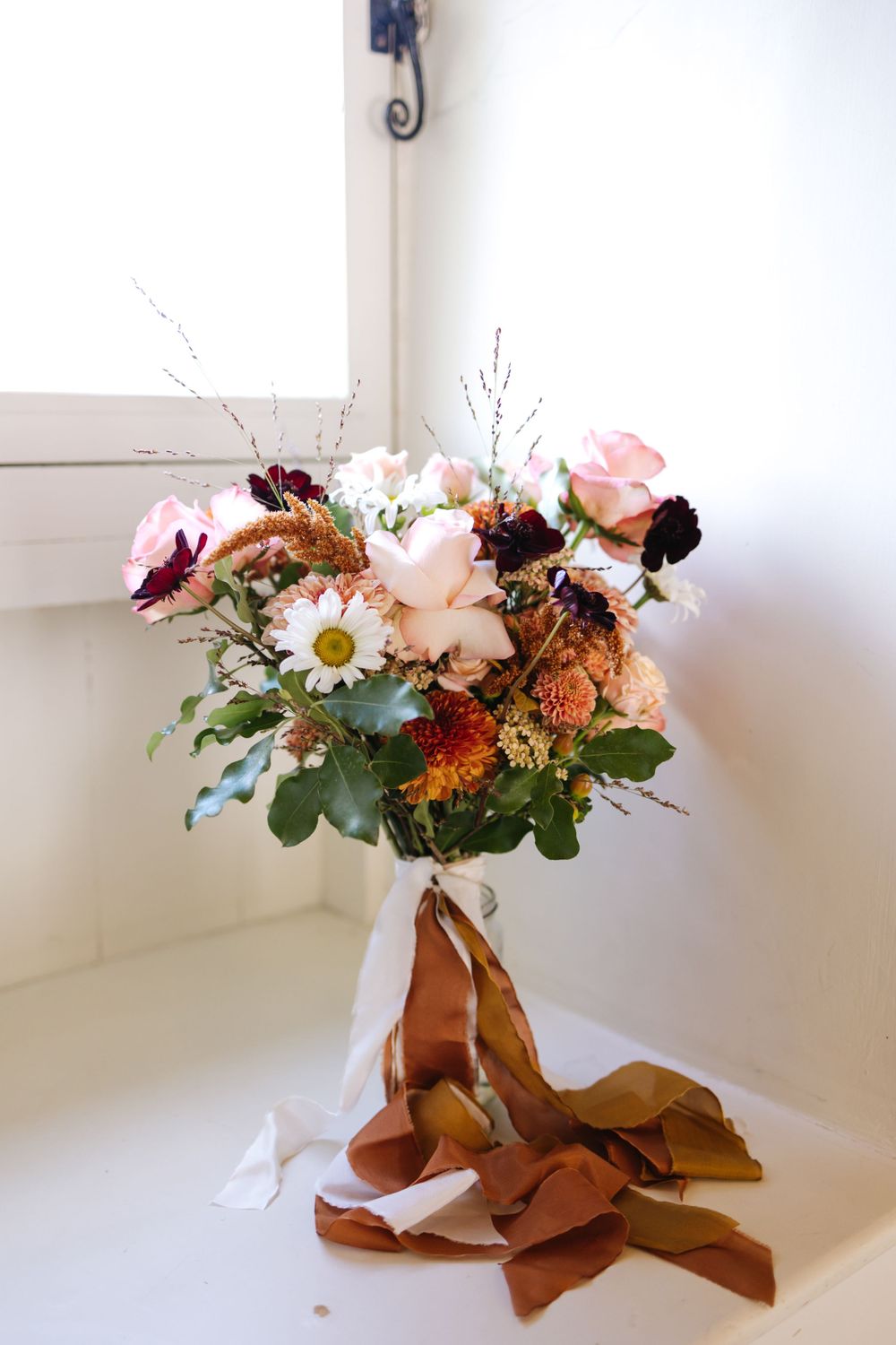 Romantic floral arrangement with roses, daisies and autumn flowers tied with flowing brown and white silk ribbons.