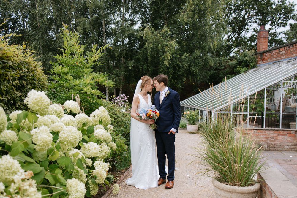 Beautiful outdoor wedding scene with hydrangeas blooming beside a greenhouse path.