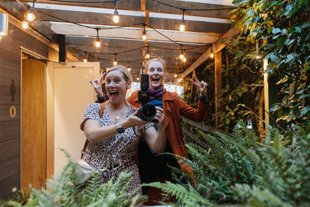 A cozy covered patio space decorated with hanging lights and lush potted plants.