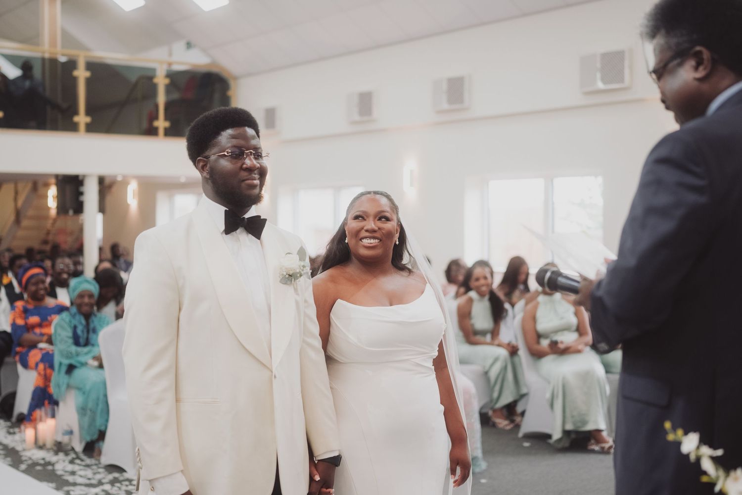 A couple in elegant white wedding attire shares a joyful moment during their ceremony.