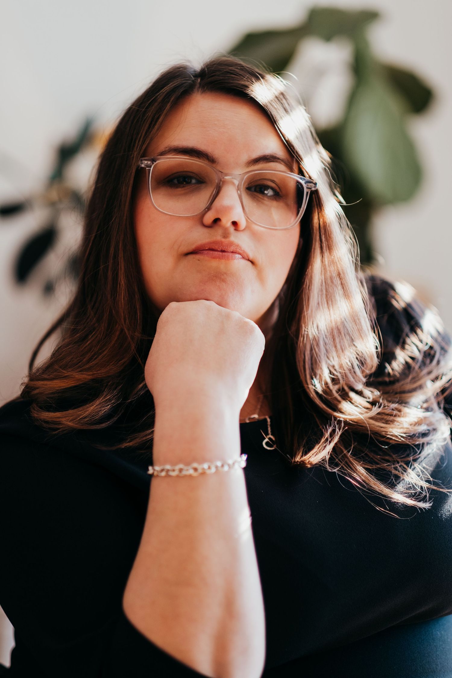 Portrait of a contemplative person with glasses and dark hair in natural lighting.