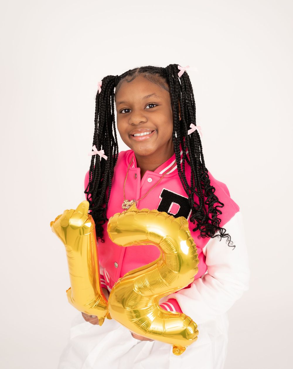 Studio portrait series showing a pink jacket and gold balloon against white background.