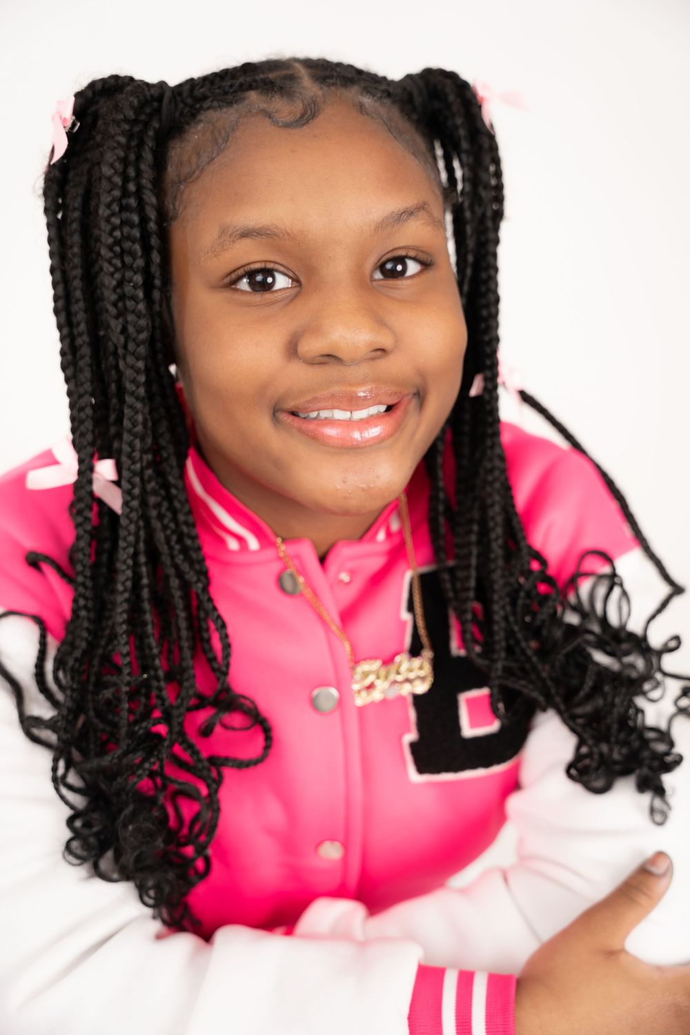 Bright studio portraits showcasing braided hairstyles with a pink jacket against white background.