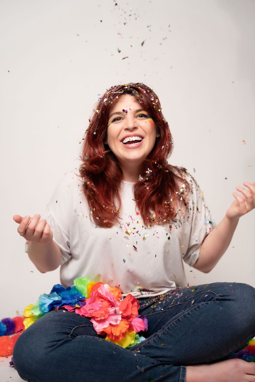Playful photoshoot with colorful confetti and jeans against white background.