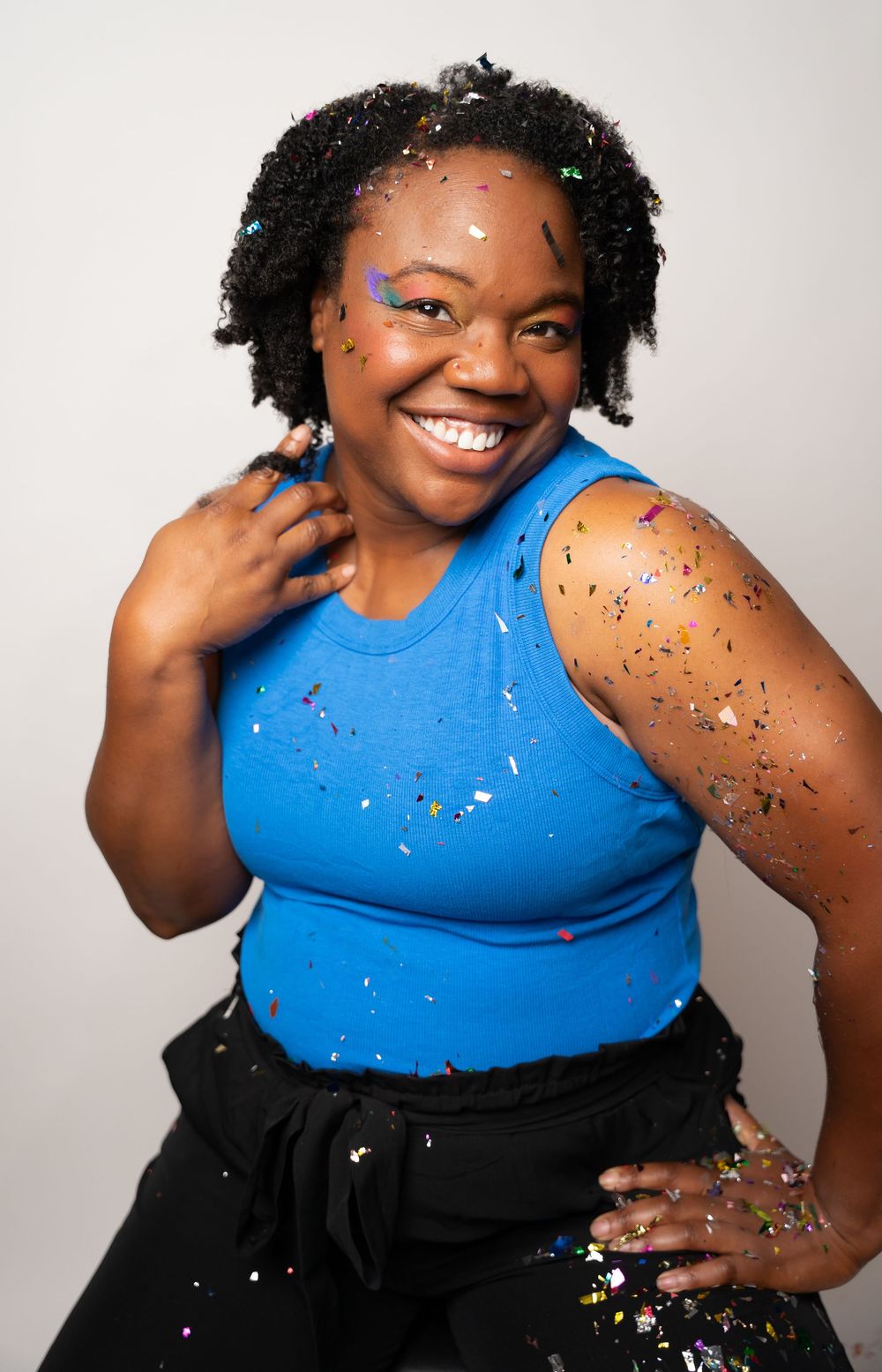 Vibrant photoshoot featuring blue tank top and black skirt with scattered glitter.