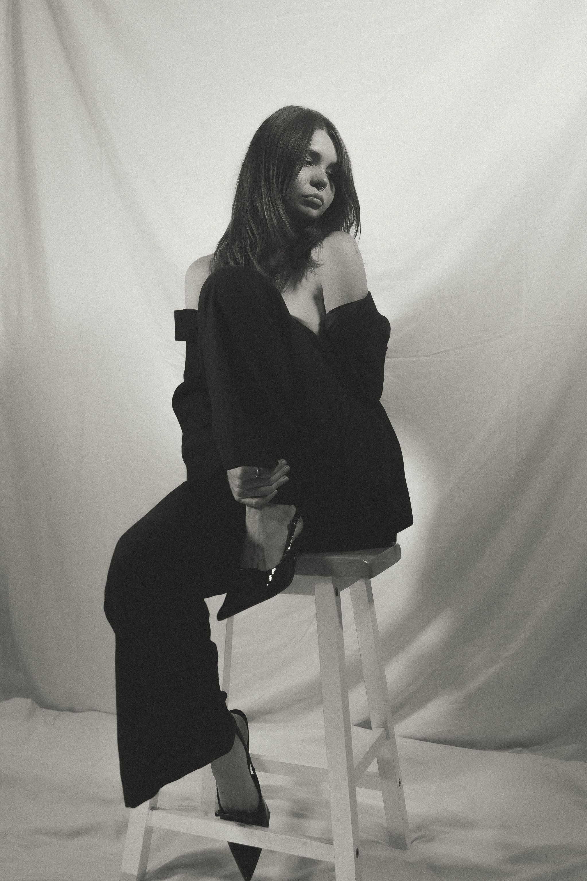 Black and white portrait series of figure posing on wooden stool against white backdrop.