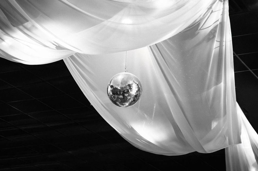 Flowing white fabric creates an elegant draped ceiling decoration with disco ball accents.
