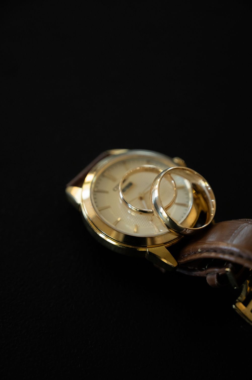 Gold vintage watch with brown leather strap displayed on dark background.