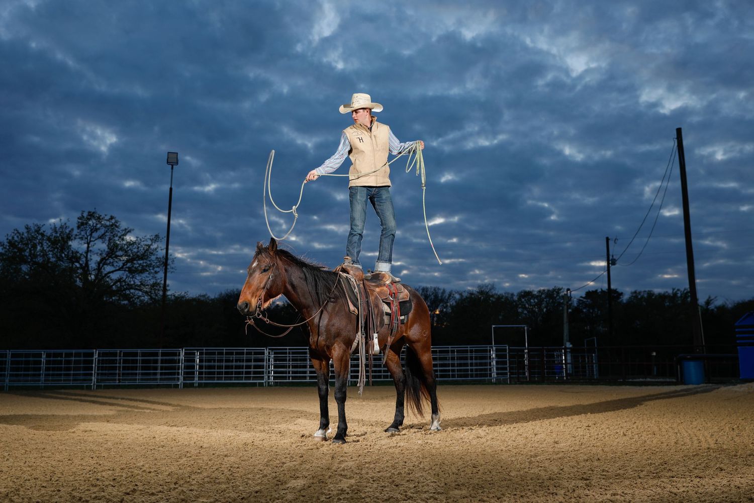 cowboy standing on top of horse throwing a lasso, off camera flash photography, dramatic portraits