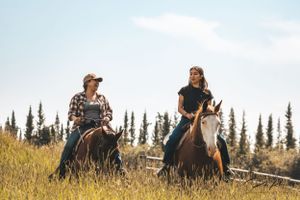Rider leading horse across a creek in Northern BC's wilderness