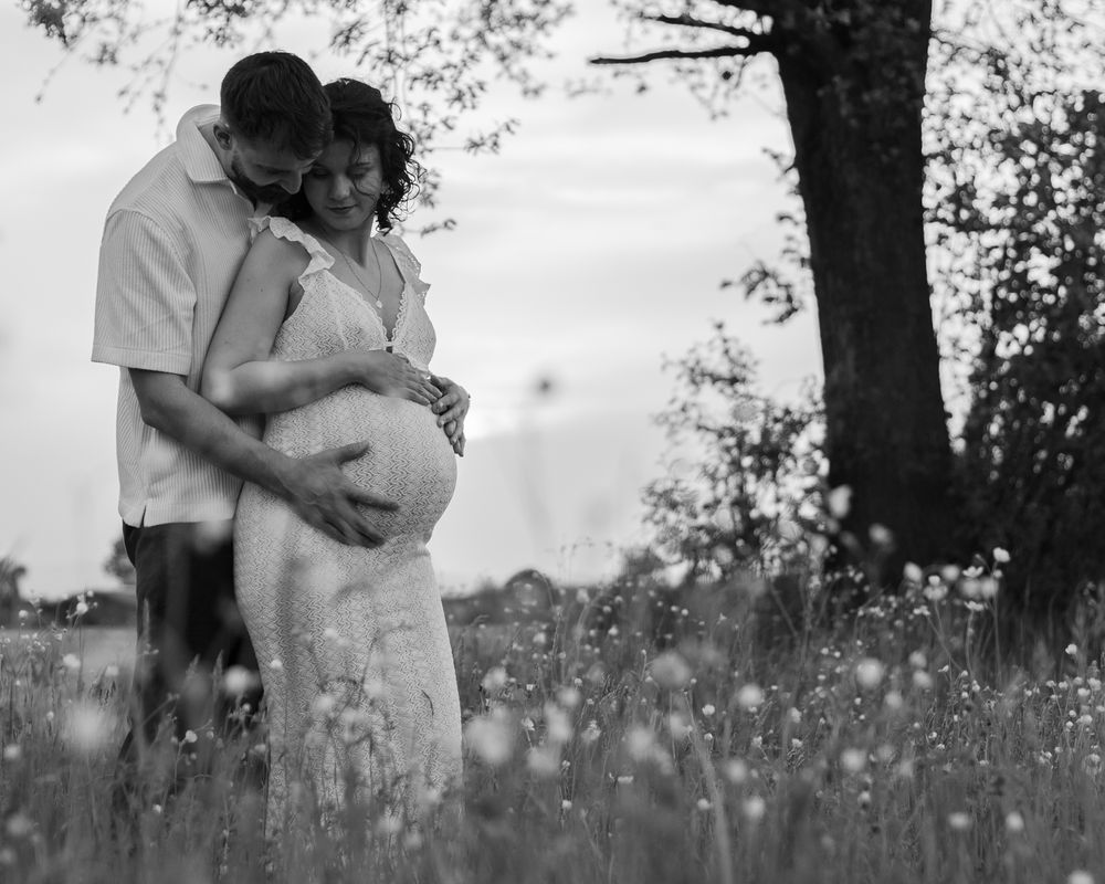 A black and white portrait of a couple embracing in a field of wildflowers.