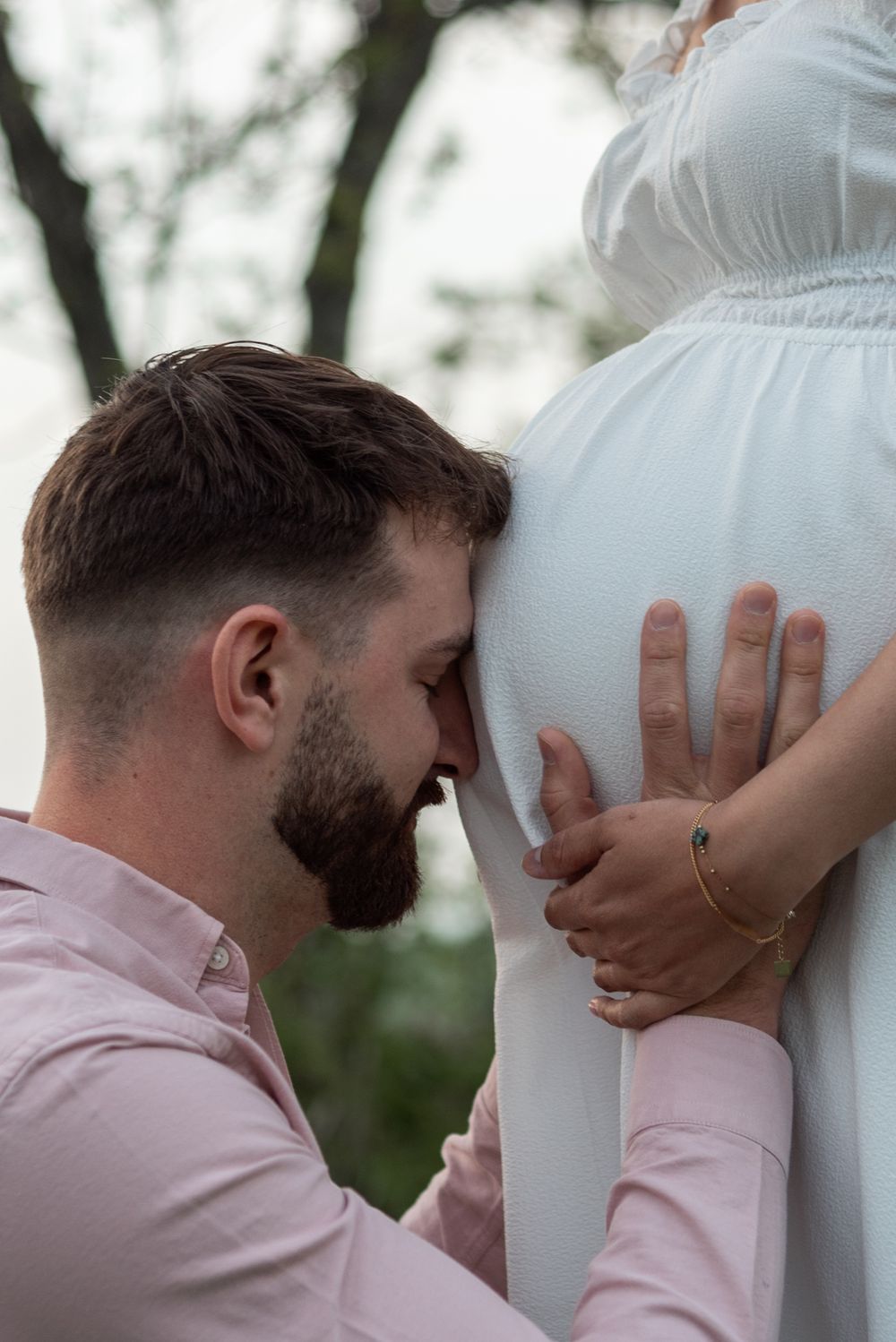 An intimate maternity photoshoot moment in a natural outdoor setting.