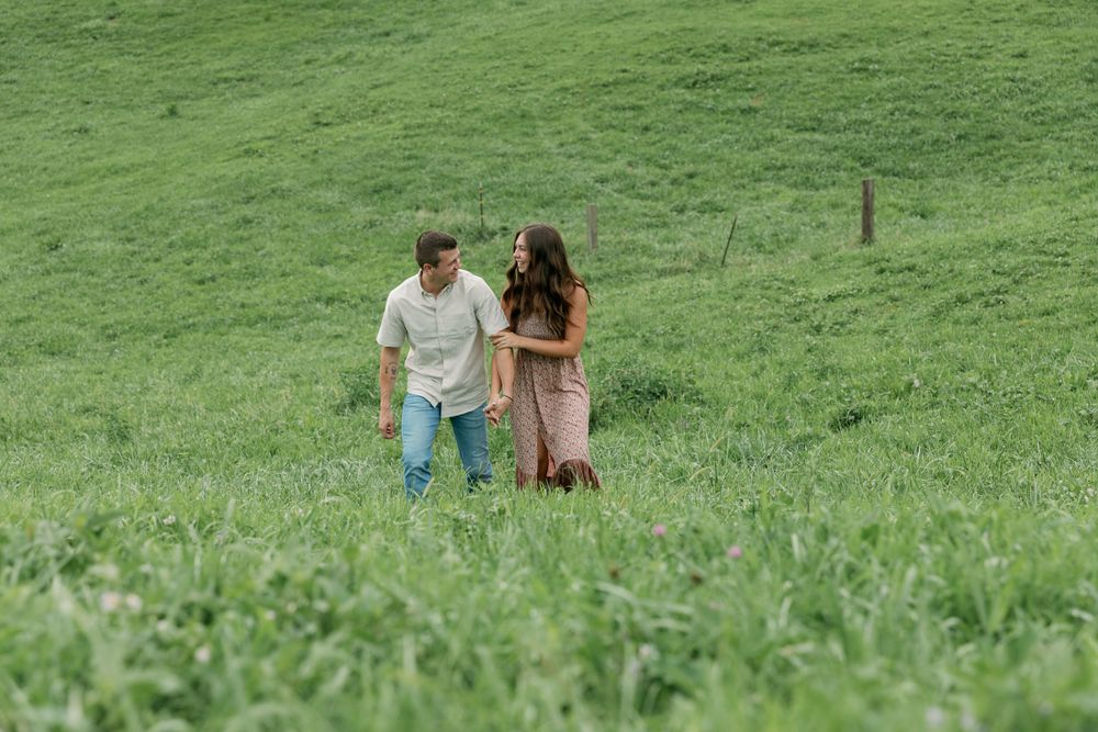 A couple walking together through a scenic green hillside meadow.