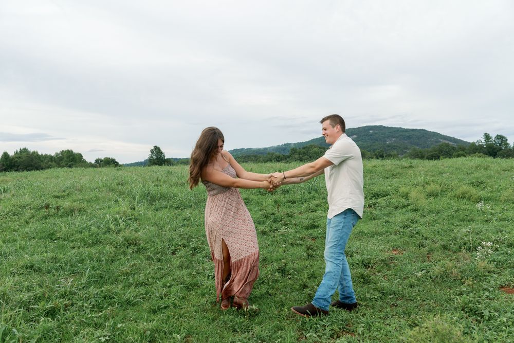 A couple shares a romantic moment in a rolling green meadow landscape.