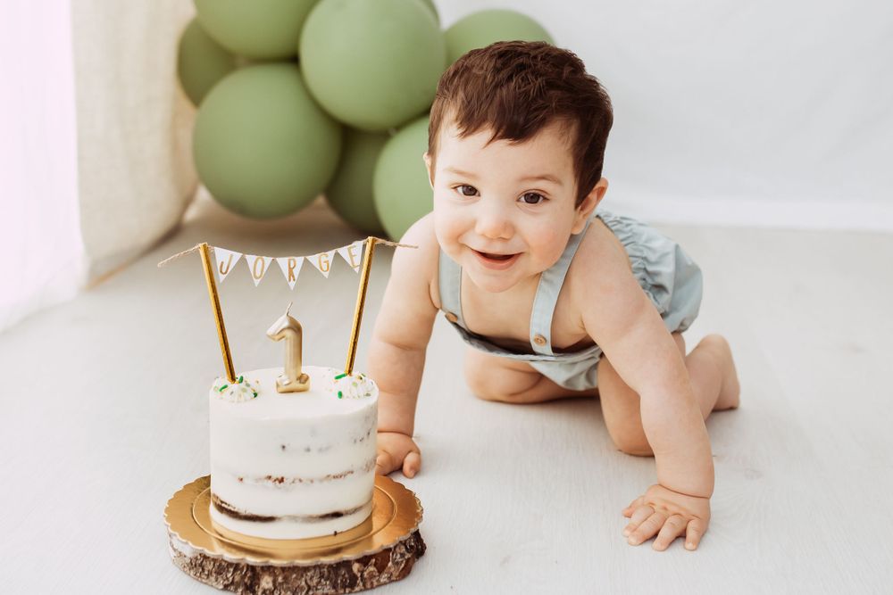 Baby's first birthday setup with green balloons and cake smash decorations.