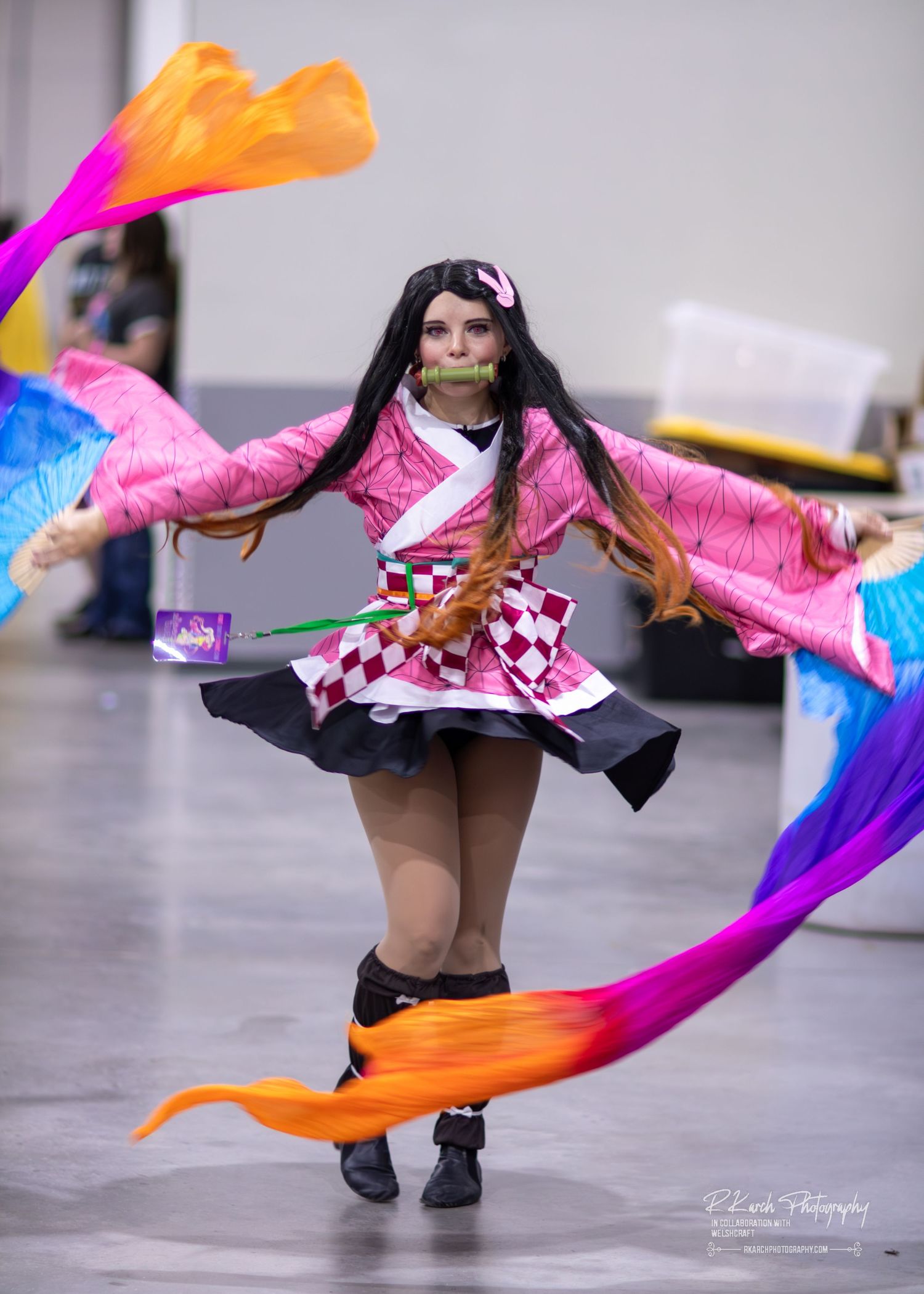 Cosplayer with bright pink hair wearing a red jacket and steampunk-style accessories.