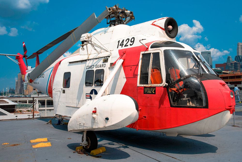 Red and white Coast Guard helicopter 1429 parked on deck against blue sky.