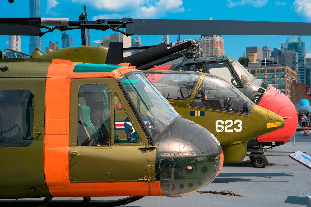 Row of vintage military helicopters with orange and olive drab paint.