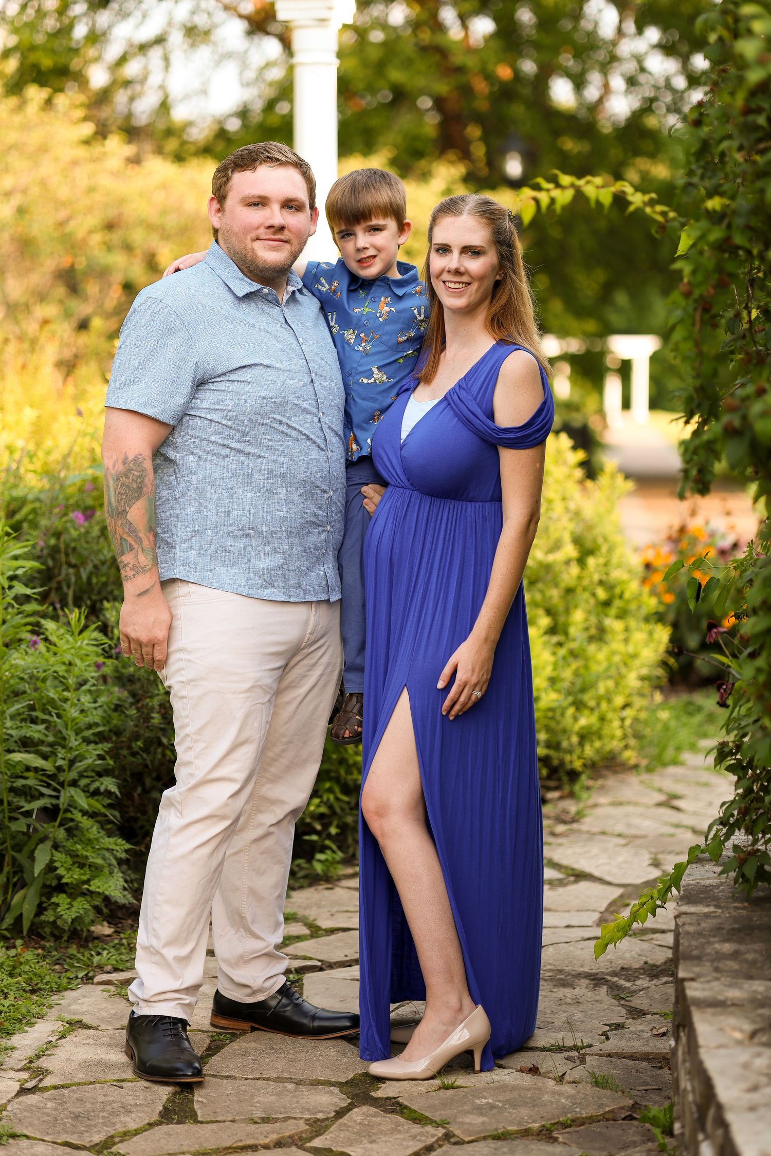 A formal family portrait taken on a stone path in a lush garden setting with blooming flowers.
