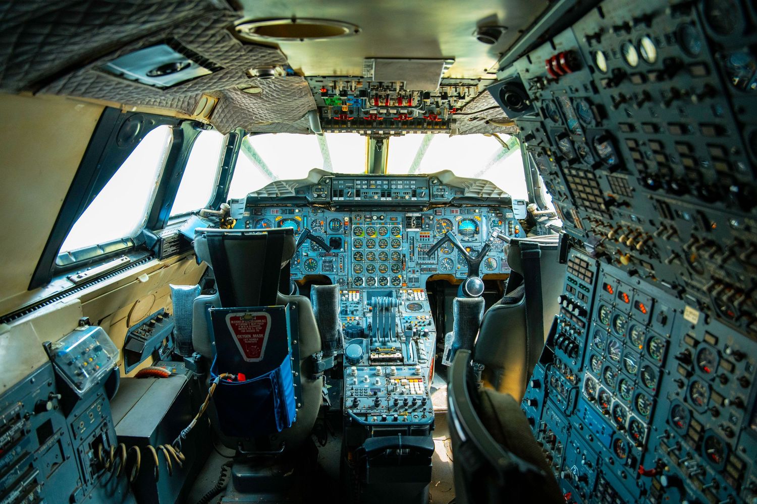 Interior view of a commercial airliner flight deck showing extensive control panels and instrumentation.