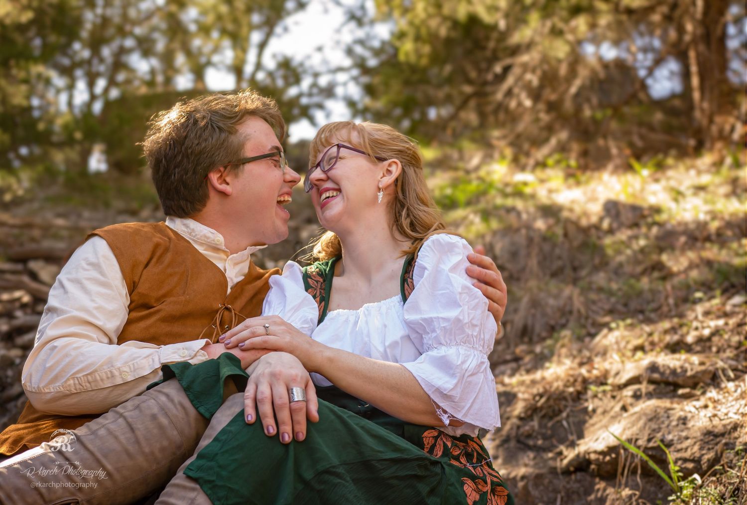 Couple in vintage countryside attire share intimate moment on hillside.