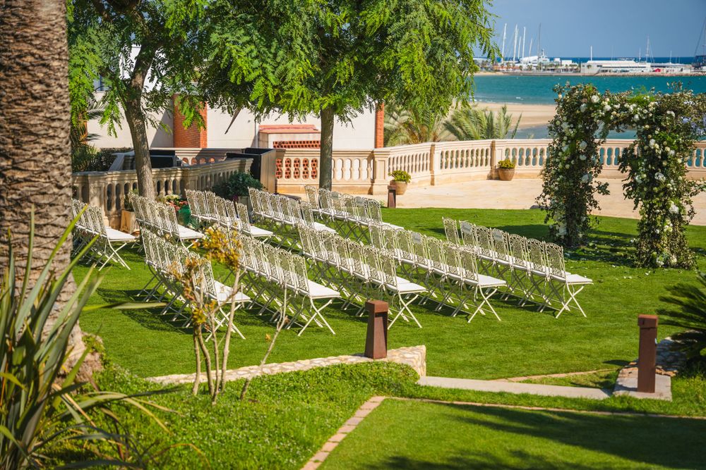 Garden wedding venue with white chairs arranged on manicured lawn overlooking the ocean.
