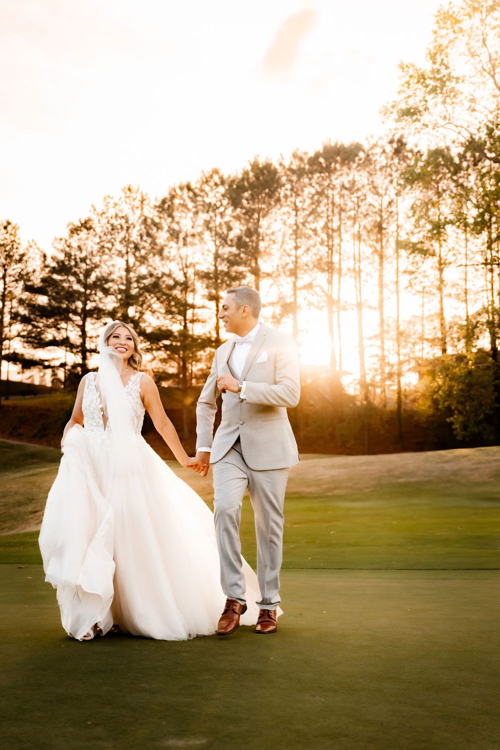 Newlyweds sharing romantic moment on golf course during golden hour.
