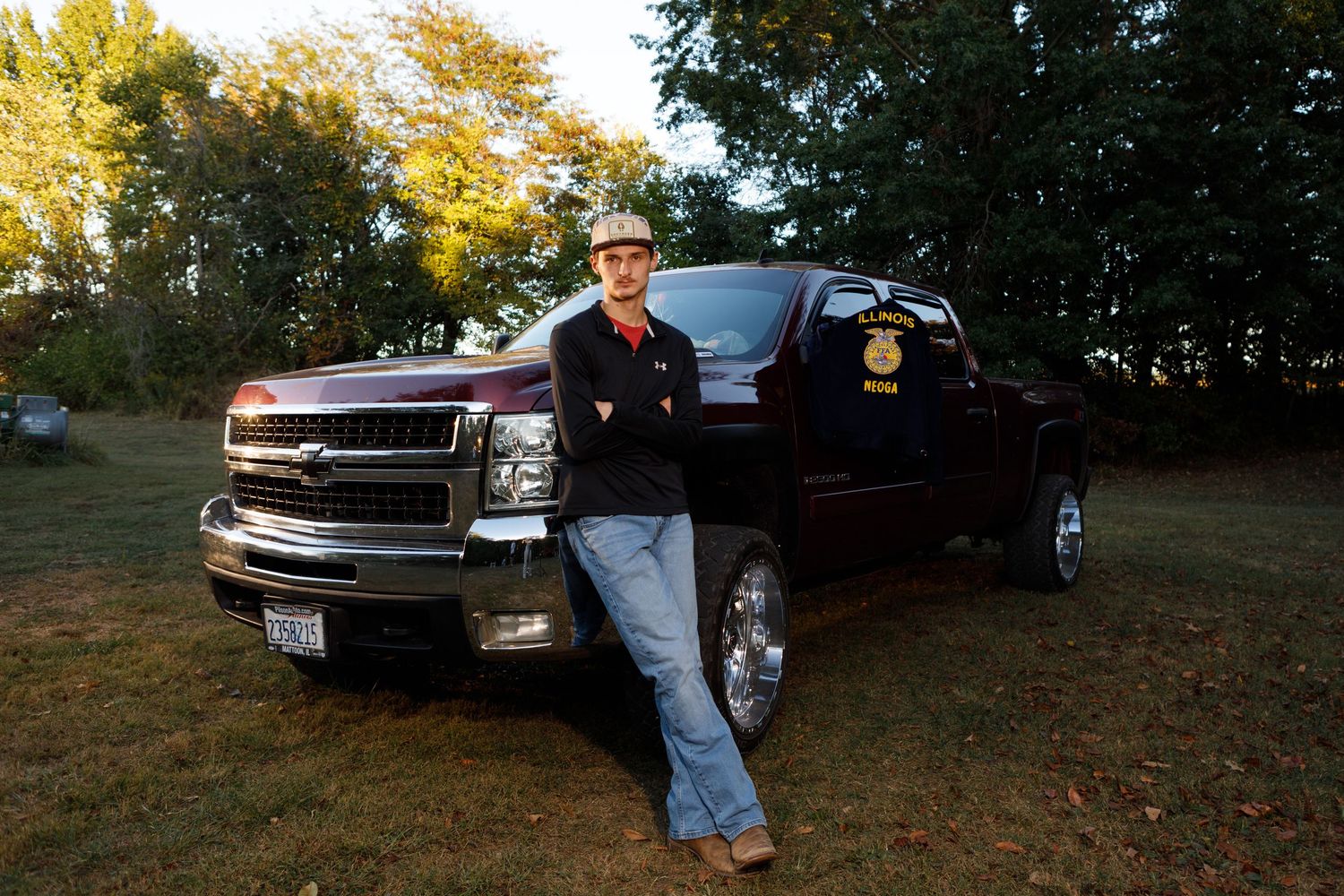 Senior boy proudly stands between his car and truck for his Neoga, Illinois senior pictures.