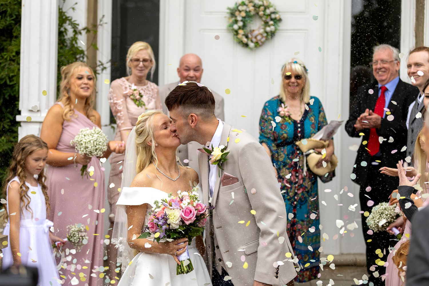 bride and groom kissing under confetti