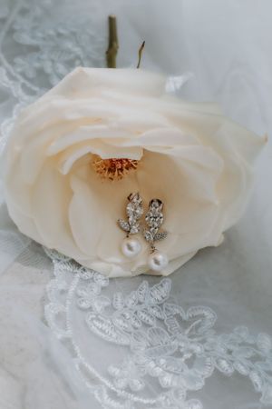 Pearl earrings nestled in a cream rose with lace detail.