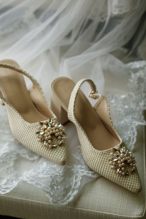 Elegant cream bridal shoes with ornate crystal embellishments displayed on lace fabric.