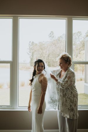 Two people by large windows during wedding preparations.