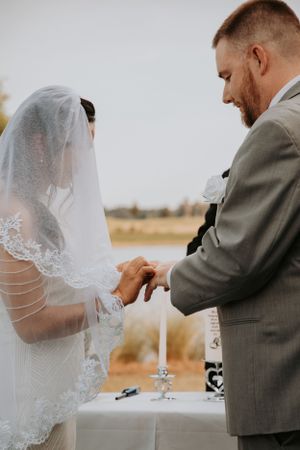 Close-up details of a wedding ceremony with delicate lace veil and gray suit.