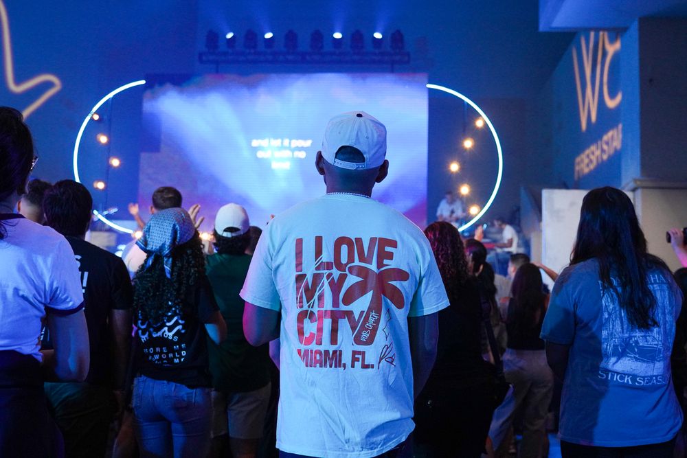 Concert attendees enjoying a show with neon blue stage lights and signage.