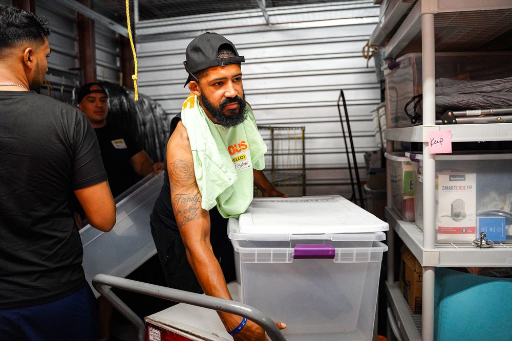 Staff members working in a storage area with plastic containers and metal shelving.