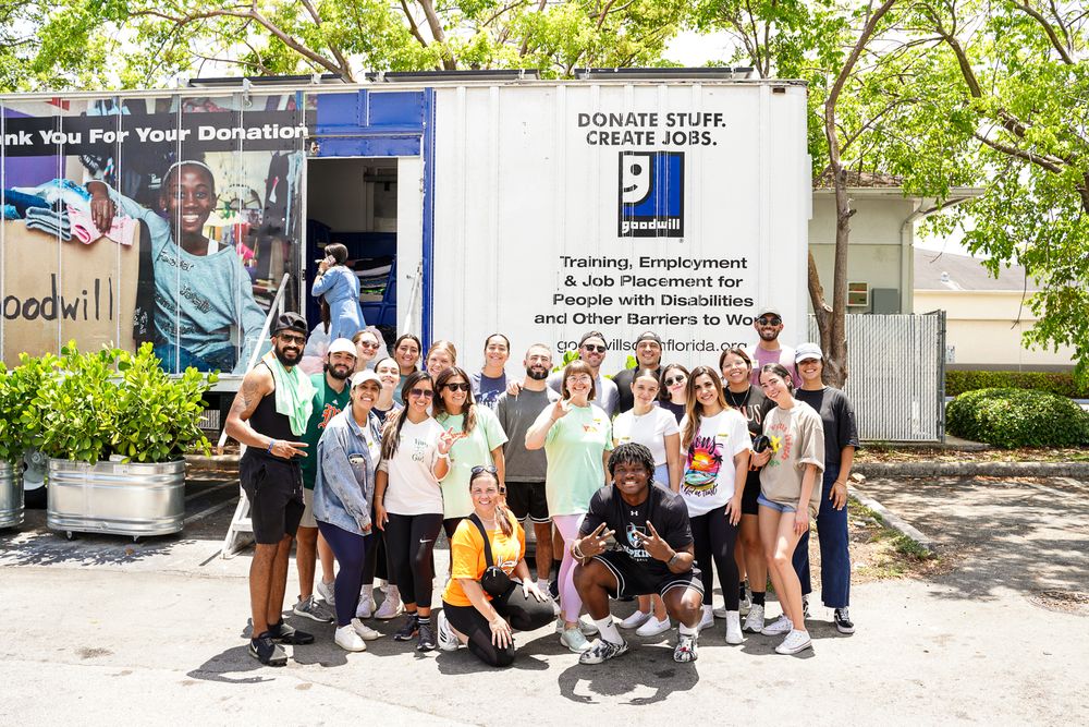 Large group posed together in front of a Goodwill donation truck.
